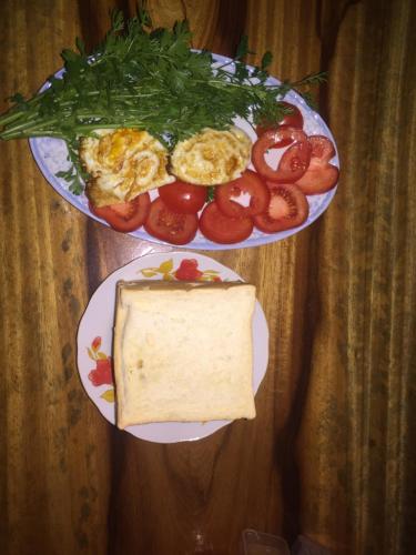 two plates of food with a sandwich and tomatoes at Nobita Homestay bắc hà in Bắc Hà