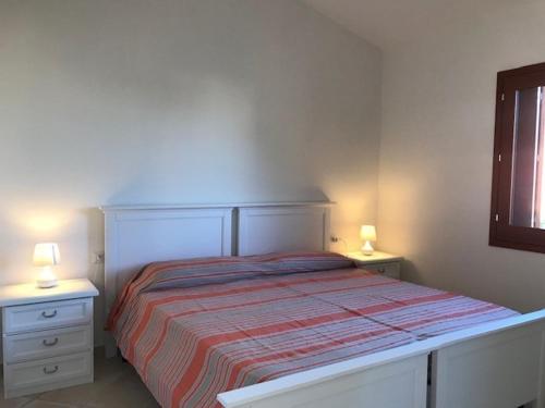 een slaapkamer met een bed met twee nachtkastjes en twee lampen bij Corallo in San Teodoro