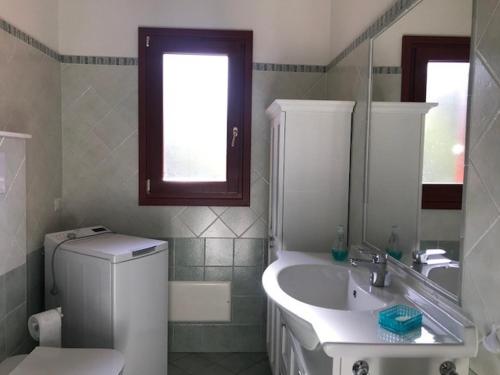 een badkamer met een wastafel, een toilet en een spiegel bij Corallo in San Teodoro
