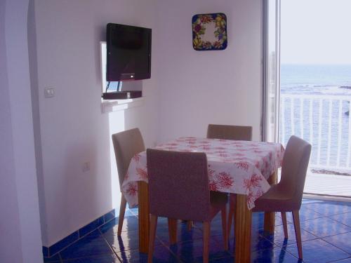 une salle à manger avec une table, des chaises et une télévision dans l'établissement Casa Mare Sole, à Villanova di Ostuni