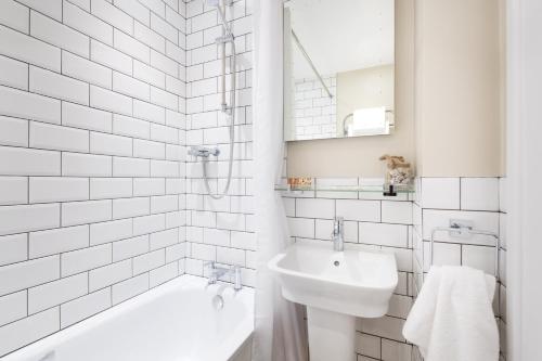 a white bathroom with a tub and a sink at The Ship Inn in Mousehole