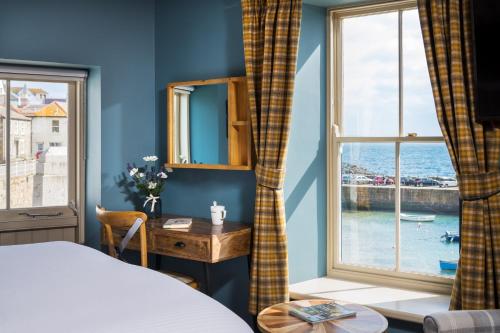 a bedroom with a bed and a desk and a window at The Ship Inn in Mousehole