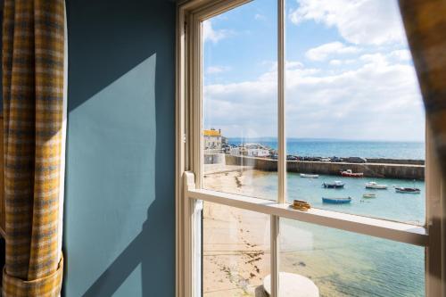 a window with a view of a beach and the ocean at The Ship Inn in Mousehole