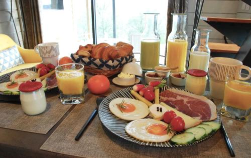 a table topped with plates of breakfast foods and orange juice at Chalet de charme climatisé, son Jacuzzi - SPA privatif et la piscine de la Maison Bleue du Gers in Savignac-Mona