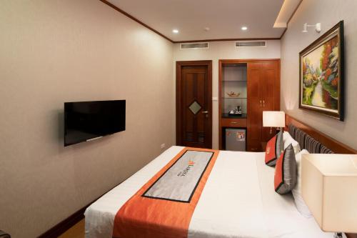 a hotel room with a bed and a flat screen tv at Hanoi Larosa Hotel in Hanoi