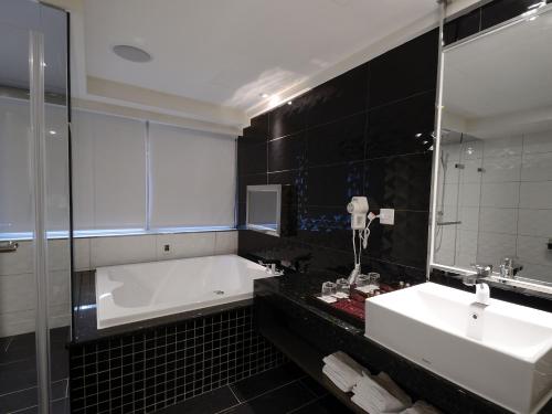a bathroom with a tub and a sink and a mirror at V-one Vogue Hotel in Taipei