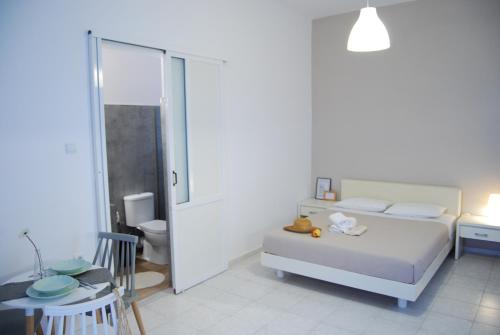 a white bedroom with a bed and a bathroom at Galini Rooms & Apartments in Finikas