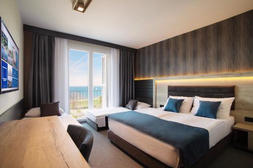 a hotel room with two beds and a large window at Dependences - San Simon Resort in Izola