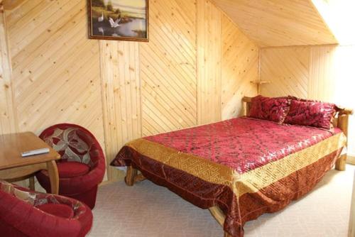 a bedroom with a bed and two chairs at Pid Yavorom in Ivano-Frankivsʼk