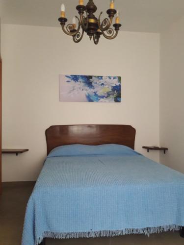a bedroom with a blue bed and a chandelier at casa maria in Sestri Levante
