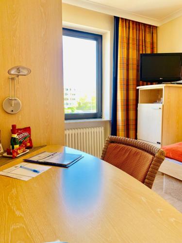 a desk in a room with a table and a window at Aparthotel Kleine Perle in Cuxhaven