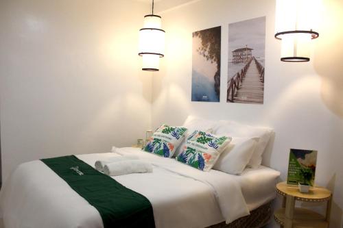 a bedroom with a bed with white sheets and pillows at Ronaldo's Inn Siargao by Cocotel in General Luna