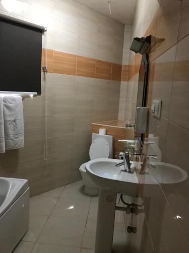 a bathroom with a white sink and a toilet at Airside Hotel in Accra