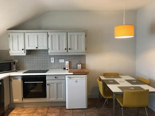 a kitchen with white cabinets and a table with chairs at Inchydoney Apt 6, Block D in Clonakilty