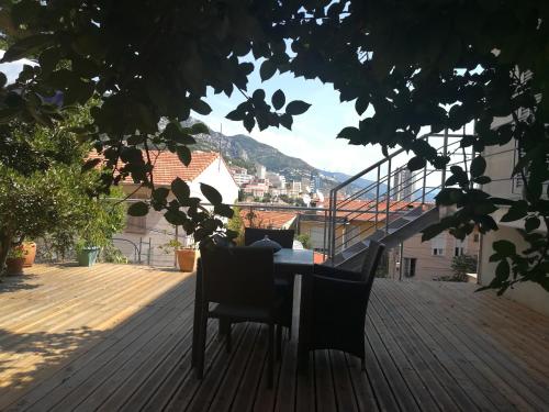 terraza de madera con mesa y sillas en el balcón en Gîtes LA Brunette, en Beausoleil