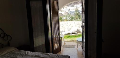 1 dormitorio con puerta que da a un patio con silla en Lovely 2 bedroom house with private garden, en Mogán