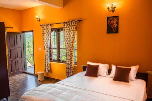 a bedroom with a bed with orange walls and a window at Sharanyam Homestay in Mananthavady