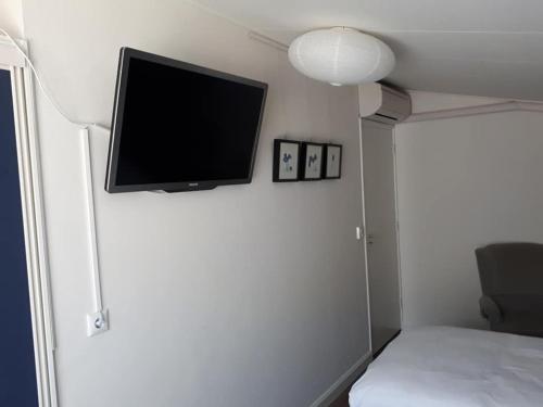 TV de pantalla plana en la pared de un dormitorio en B&B De Blauwe Tulp, en Noord-Scharwoude
