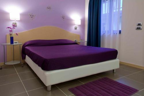 una camera da letto con un letto con lenzuola viola e una finestra di Palazzo Mulada a Frattamaggiore