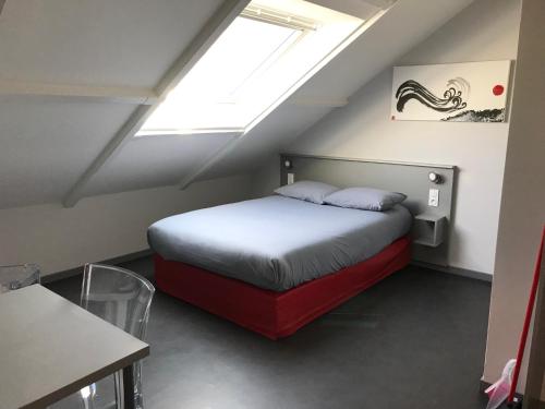 ein Schlafzimmer mit einem Bett im Dachgeschoss mit einem Fenster in der Unterkunft Smart Living in Saint-Nazaire