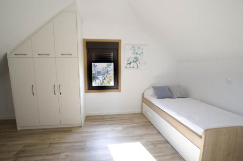 a white bedroom with a bed and a window at Casa A Rotea in Vilaboa