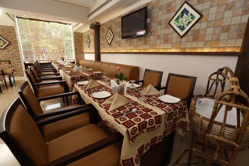 a restaurant with a long table and chairs and a television at PEARL ROYAL INTERNATIONAL HOTELS & RESORTS PVT LTD in Thodupuzha