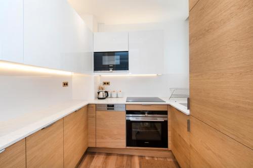 - une cuisine avec des murs blancs et des placards en bois dans l'établissement Luxury Montaigne apartment, à Paris