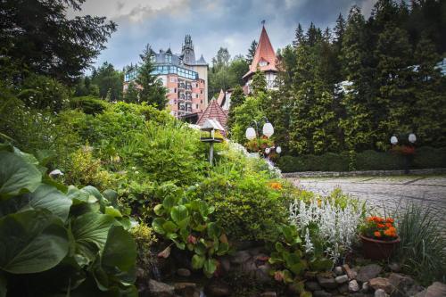 a garden with flowers and a building in the background at Hotel Las Piechowice in Szklarska Poręba