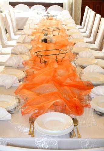 a long table with white plates and orange napkins at Park Hotel in Rzepin