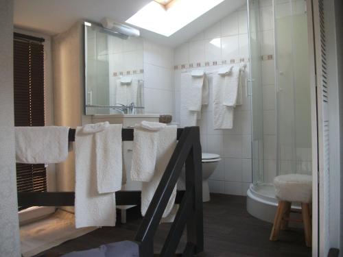 a bathroom with white towels and a sink and a tub at L'Inattendue in Chaumont