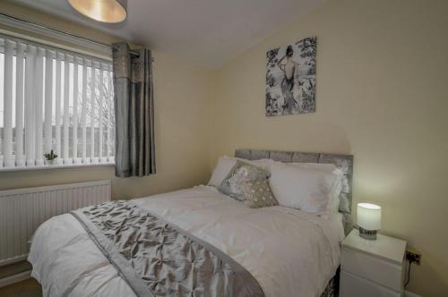 a bedroom with a bed with white sheets and a window at Newly Renovated Modern Home in Manchester