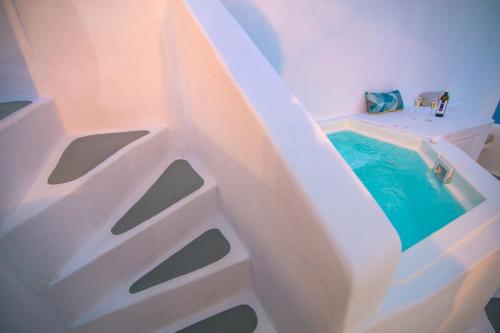 a bathtub with a plunge pool in a room at Hector Cave House in Oia