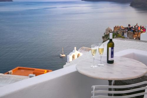 una mesa con 2 copas de vino en el balcón en Hector Cave House, en Oia