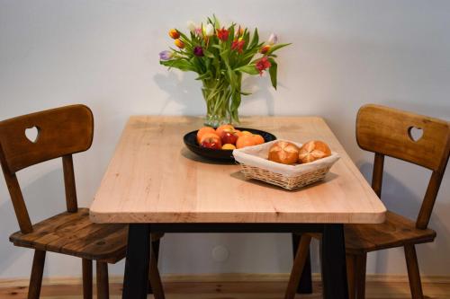 a table with a bowl of fruit and a vase of flowers at Spitzing Lodge Ferienwohnungen - Wanderparadies in den Bergen in Spitzingsee