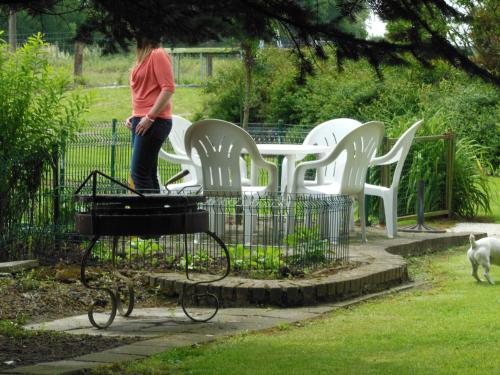 a woman standing on a grill next to white chairs at Poezelhoekvallei Loft in Zonnebeke