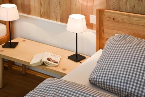 a bedroom with a bed and a table with two lamps at Spitzing Lodge Ferienwohnungen - Wanderparadies in den Bergen in Spitzingsee