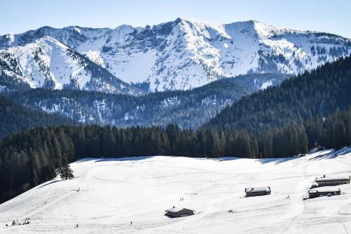 a snow covered mountain with houses in the foreground at Spitzing Lodge Ferienwohnungen - Wanderparadies in den Bergen in Spitzingsee