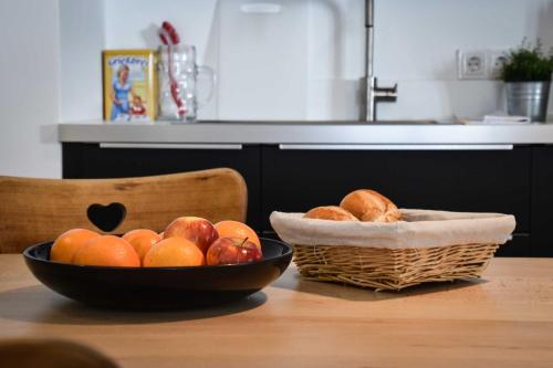 a table with two bowls of fruit and a basket of bread at Spitzing Lodge Ferienwohnungen - Wanderparadies in den Bergen in Spitzingsee