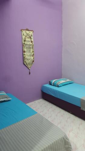 two twin beds in a room with purple walls at Cottage Muslim Homestay ByWawaSha in Tanjung Malim