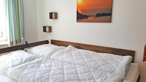 a bedroom with a white bed with a picture on the wall at Apartment 8 in Heiligenhafen