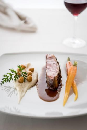 a plate of food with meat and carrots on a table at Das Panorama Designhotel in Caldaro