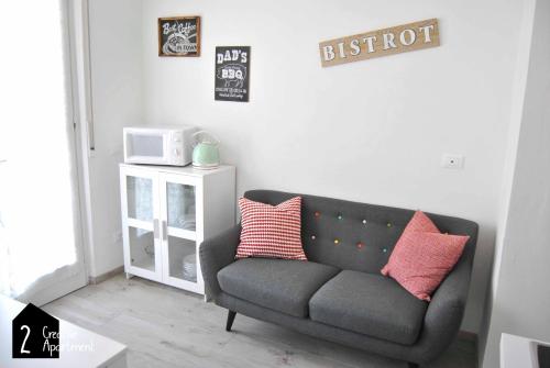 een woonkamer met een grijze bank en een magnetron bij Creative Apartment in Dro