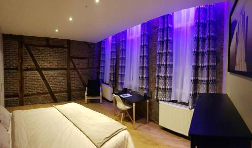 a bedroom with a bed and a desk and purple lights at The Mind Box in Liège