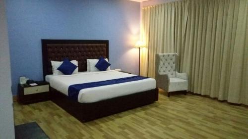 a bedroom with a large bed and a chair at The Kannelite in Jamshedpur