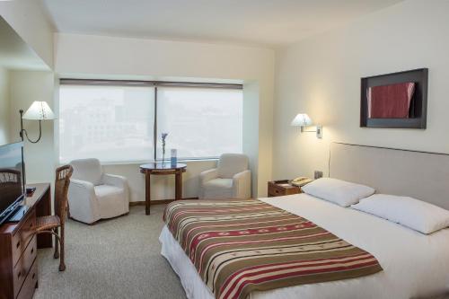 a hotel room with a bed and a desk and chairs at Almacruz Hotel y Centro de Convenciones (Ex Galerías) in Santiago