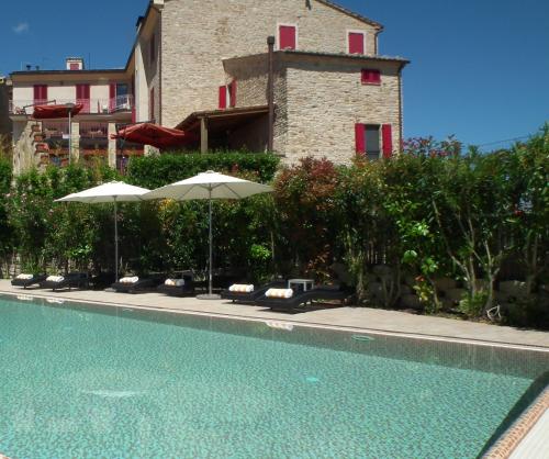 a swimming pool with umbrellas and chairs and a building at Hotel Leone in Montelparo