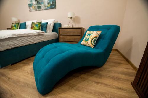 a blue chair in a bedroom with a bed at IMPERIAL ROOMS - ULTRACENTRAL - jacuzzi cu hidromasaj in Oradea