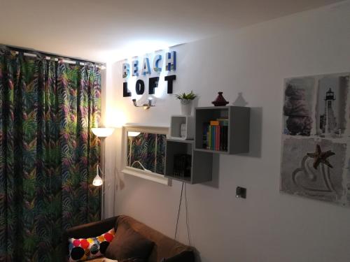 ein Wohnzimmer mit einem Sofa und einem Schild an der Wand in der Unterkunft Apartamento Beach Loft Las Canteras in Las Palmas de Gran Canaria