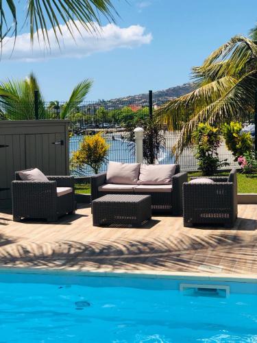 a couch and chairs next to a swimming pool at Hotel Pelican in Schœlcher