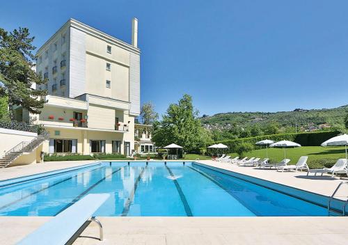 a large swimming pool with chairs and a building at Hotel Fiuggi Terme Resort & Spa in Fiuggi